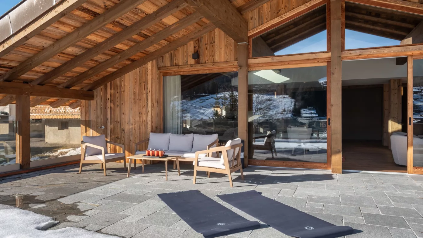 Two Emerald Stay yoga mats on the snowy terrace of a chalet.