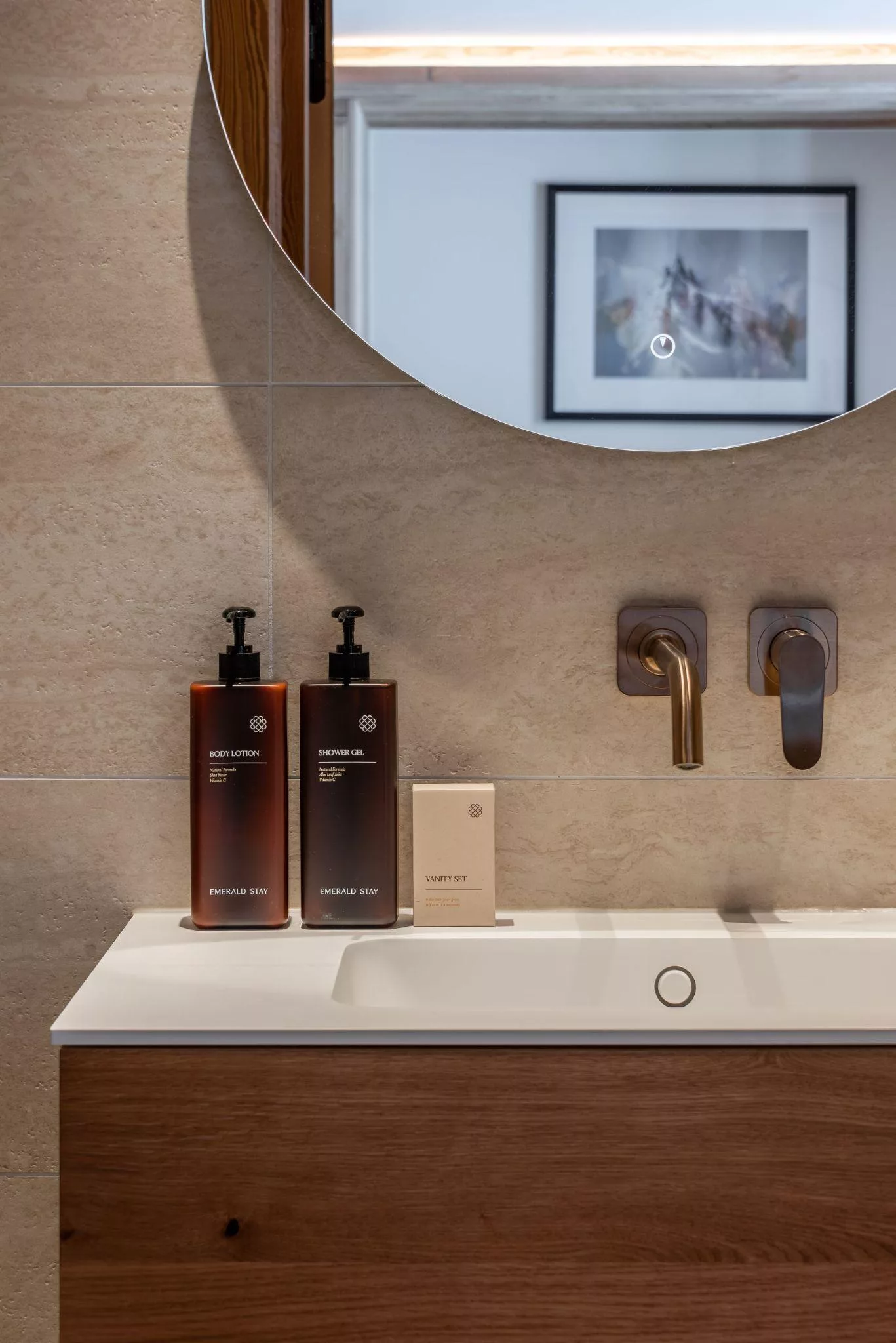 Une vasque en pierre claire, des flacons ambrés et un savon dans une salle de bain d’hôtel.
