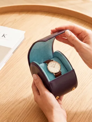 A watch in a deep blue leather case.