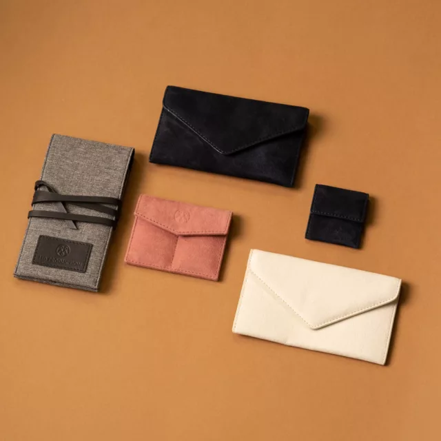 Watch service pouches in black, ivory and dusty-pink suede-like fabric, and a canvas pouch tied with leather