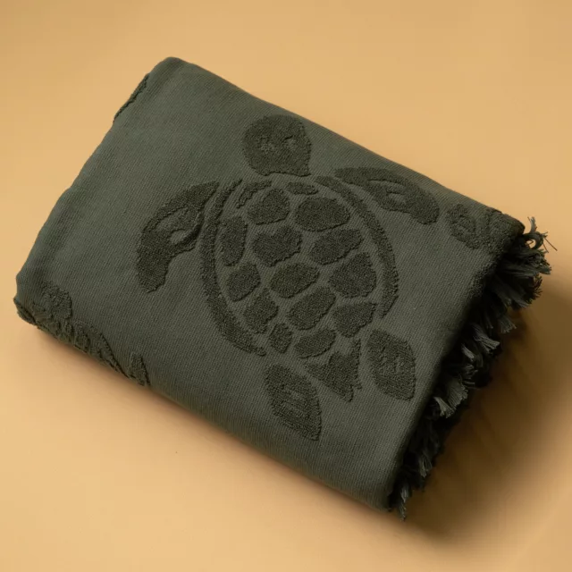 Folded deep green fouta with a tone-on-tone terry motif on a flat weave and fringed edge, bespoke wellbeing
