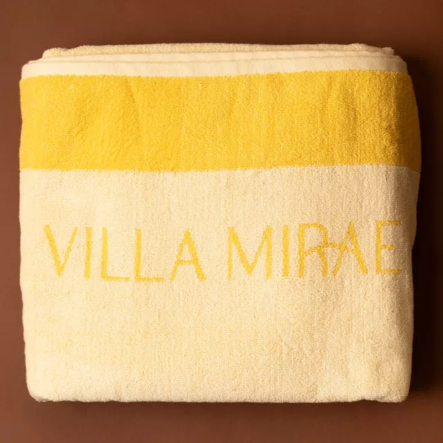 Folded cream terry bath towel with a broad yellow band and woven lettering, bespoke wellbeing