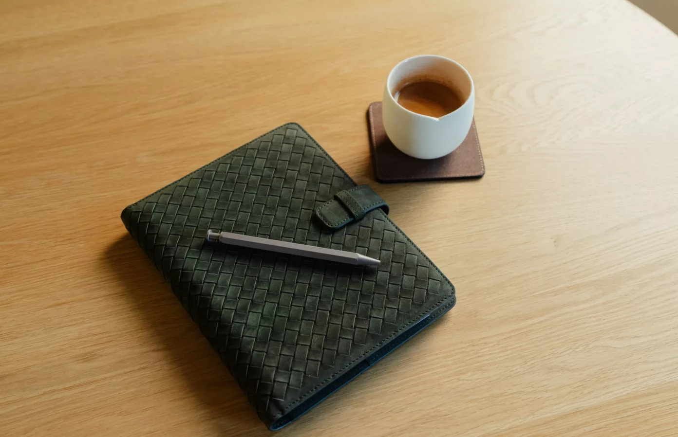 Green woven leather notebook, pen and leather coaster on a table, bespoke corporate gifts, Maison Maëstra