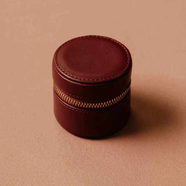 Écrin de voyage pour bague, cylindrique, en cuir bordeaux lisse fermé par un zip doré, étui à bijoux de voyage, Maison Maëstra
