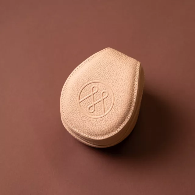 Écrin de voyage pour montre en cuir grainé poudre, en forme de galet, zippé, monogramme embossé sur le dessus, Maison Maëstra