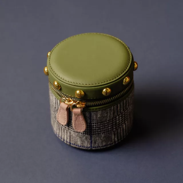 Écrin de voyage rond pour montre, couvercle en cuir vert olive clouté d’or, corps en tissu prince-de-galles, double zip doré