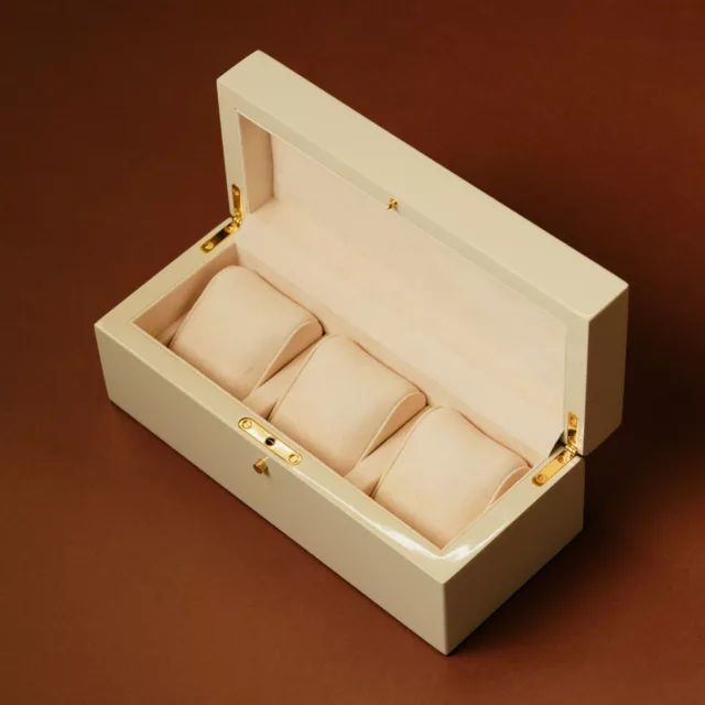 Coffret en bois laqué crème ouvert sur trois coussins de montres, charnières dorées, Maison Maëstra
