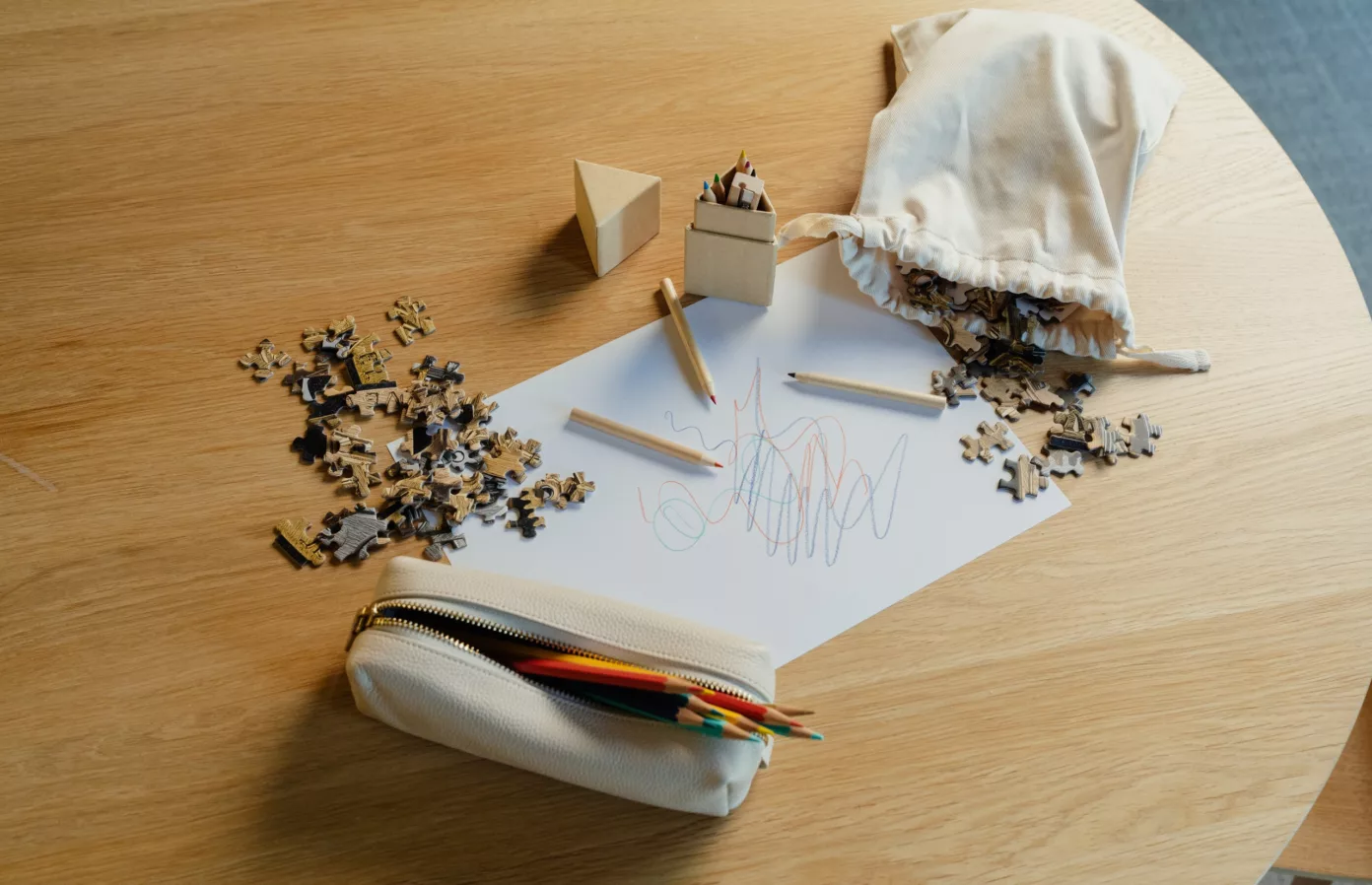 Puzzle, crayons de couleur, dessin et trousse zippée sur une table en bois, attentions pour enfants, Maison Maëstra