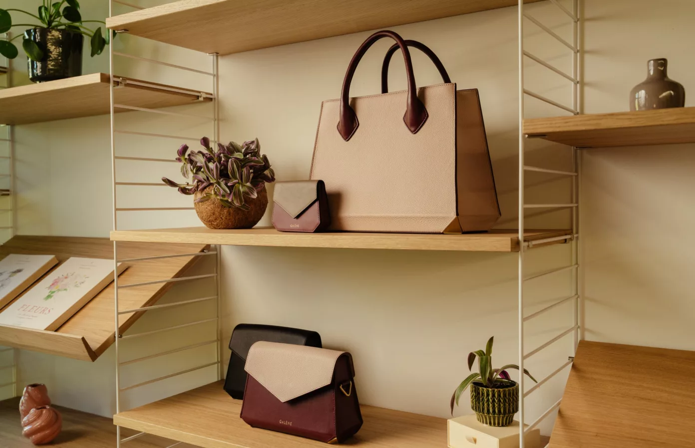 Blush, burgundy and black leather bags on wooden shelves, bespoke leather goods, Maison Maëstra