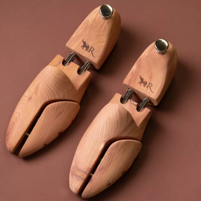 Pair of pale wooden shoe trees with twin metal rods and a monogram engraved on the heel, bespoke guest room accessories