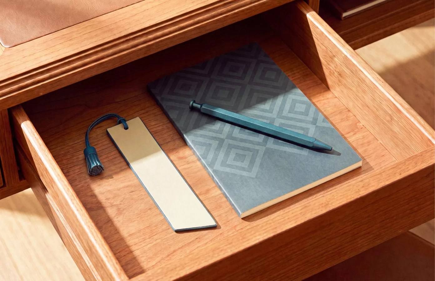 Notebook, pen and tasselled bookmark in a guest room desk drawer, bespoke guest room accessories by Maison Maëstra