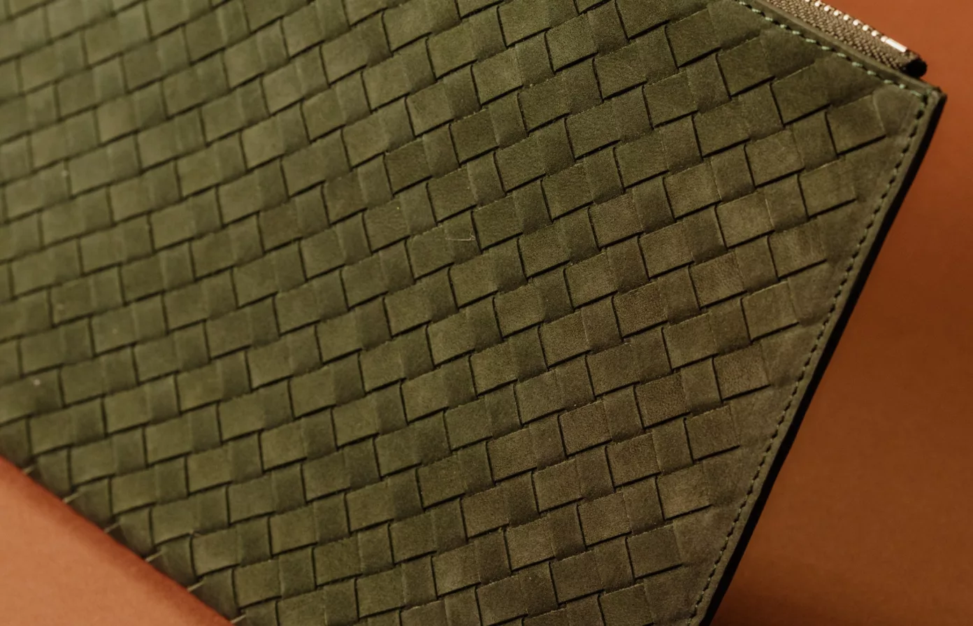 Un cuir tressé vert olive posé sur un cuir lisse terracotta.